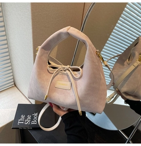 Detail of light pink canvas bag with leather brand logo label and drawstring bow detail