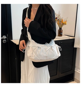 Détail du sac à bandoulière en nylon blanc avec nœud à cordon et texture plissée douce