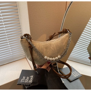 Detail of beige crescent bag with decorative silver chain and pearl strand accent