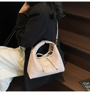 Close-up of beige corduroy shoulder bag with decorative bow on wooden stairs