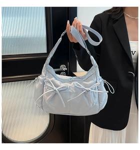 Détail du sac bandoulière en nylon matelassé bleu clair avec nœuds latéraux décoratifs