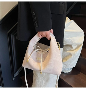 Detail of beige corduroy hobo bag featuring drawstring accents and golden hardware