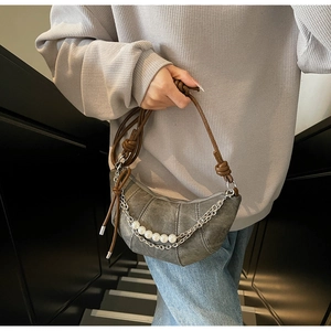 Dettaglio della borsa a mezzaluna grigia con catena d'argento e perle per un look unico