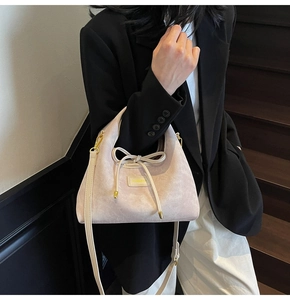 Close-up of matte textured handbag with decorative bow and premium gold metal hardware