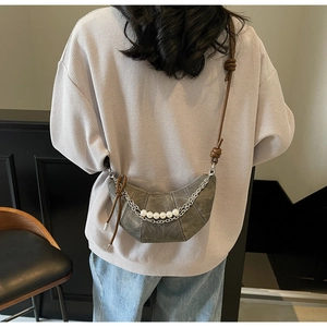 Detail of grey crescent bag with silver chain and pearl accents on brown leather strap