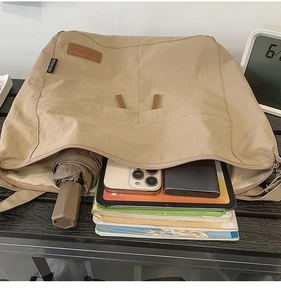 Detail view of the large capacity khaki tote bag showing books and gadgets inside