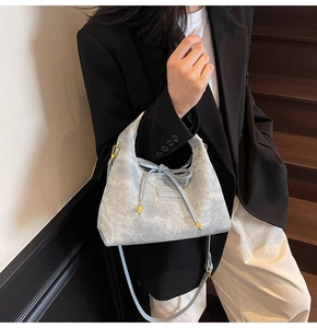 Close-up of textured light blue hobo bag with drawstring and gold metal accents