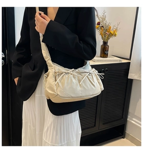 Détail du sac hobo plissé crème avec nœuds coulissants et tissu en nylon texturé