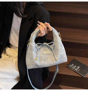 Detail of light blue corduroy shoulder bag with gold hardware and elegant bow decoration