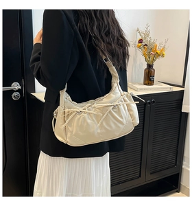 Détail du sac bandoulière croissant en nylon crème avec plis et nœuds décoratifs