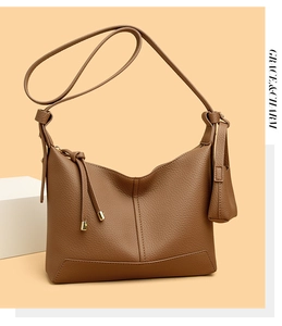 Detail of brown litchi pattern leather shoulder bag with long tassel and adjustable strap