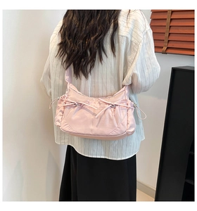 Détail du sac à bandoulière en nylon rose clair avec nœuds et cordons latéraux