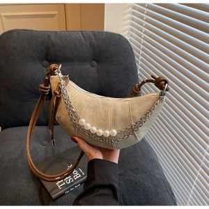 Detail of crescent shoulder bag featuring double silver chains and large pearl accents