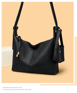 Detail of black pebbled leather hobo bag with mini pouch on warm orange background