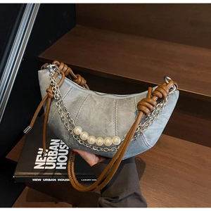 Dettaglio della borsa a mezzaluna in denim azzurro con manico intrecciato e perle