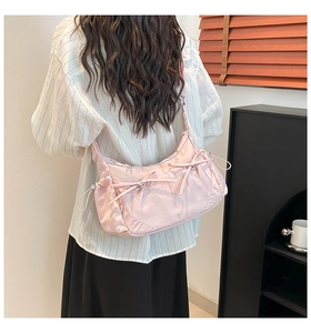 Vue portée d'un sac à bandoulière rose plissé avec nœuds et finition satinée chic