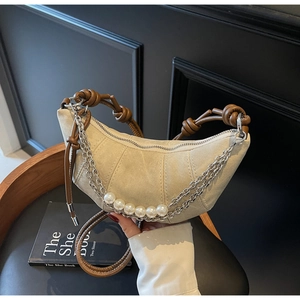 Detail of beige canvas crescent bag featuring brown leather knot and pearl chain