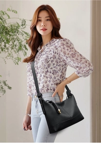 Close-up of black lychee grain leather crossbody bag with elegant gold hardware detail
