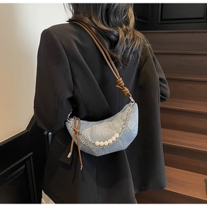Detail of light blue crescent bag featuring large pearl chain and brown leather strap