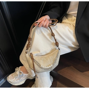 Dettaglio della borsa a mezzaluna in camoscio beige con catena d'argento e perle bianche