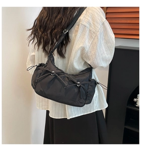Détail du sac bandoulière en nylon noir avec cordons réglables et design plissé chic