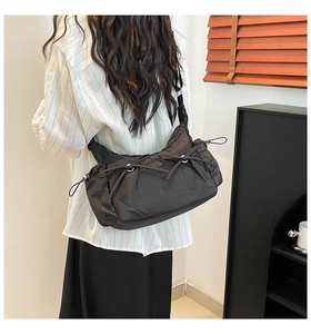 Détail d'un sac bandoulière en nylon noir avec des rubans élégants et un design froncé