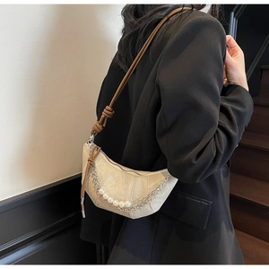 Detail of contrast crescent bag with pearl chain and dark brown knotted strap detail
