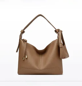 Detailed view of brown lychee grain leather shoulder bag with stylish tassel charm