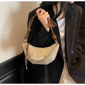 Dettaglio della borsa a mezzaluna beige con eleganti perle e tracolla marrone a nodi