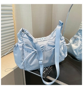 Détail du sac bandoulière en nylon bleu clair avec des nœuds de serrage décoratifs