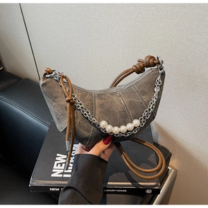 Detail of grey canvas crescent bag featuring decorative pearl and silver metal chains