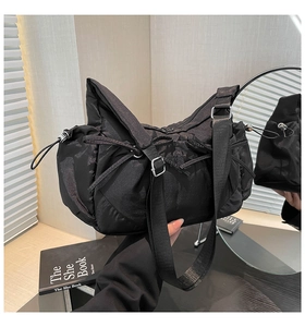 Détail du sac à bandoulière en nylon noir avec sangle réglable et cordon de serrage latéral