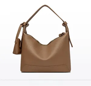 Detail view of brown lychee grain leather crossbody bag with knot handle and texture