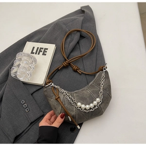 Dettaglio borsa a mezzaluna in denim grigio con catene d'argento e perle bianche