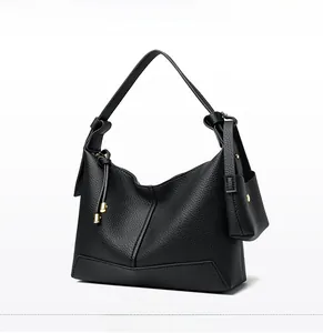 Detail of black lychee grain leather crossbody bag with gold hardware and small pouch