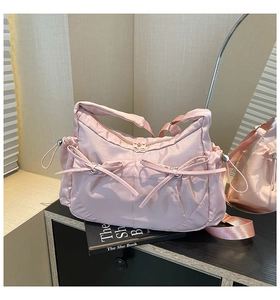 Vue détaillée du sac à bandoulière rose pâle en satin avec nœuds décoratifs et cordons