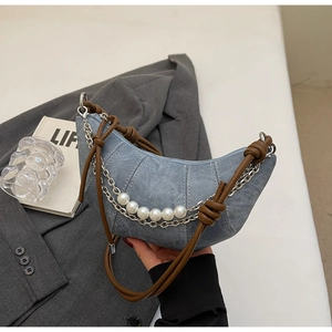Blue denim crescent bag detail featuring a silver chain, white pearls and brown handle