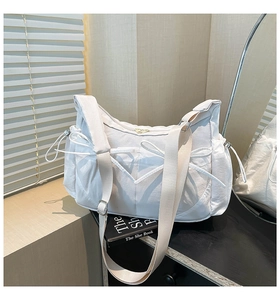 Détail d'un grand sac cabas blanc avec nœud décoratif et poches latérales à cordon