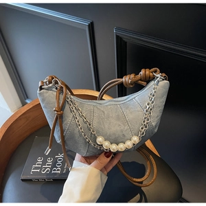 Close-up of washed denim crescent bag with pearl chain and woven rope handle detail