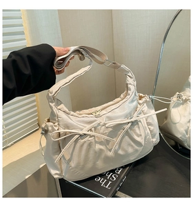 Détail du sac décontracté crème avec nœud décoratif et large bandoulière réglable