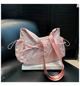 Détail du sac fourre-tout en nylon rose avec texture soie, nœuds et bandoulière large