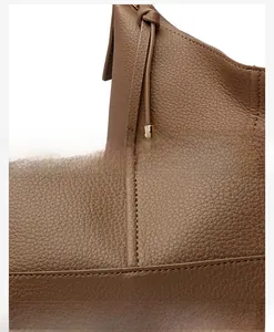 Close-up of brown lychee grain leather texture with precision stitching and metal buckle