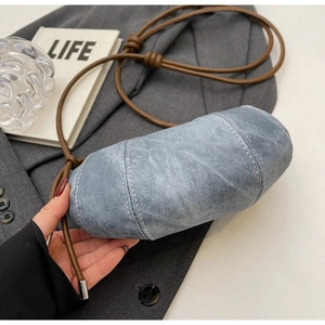 Dettaglio borsa a mezzaluna in denim blu con cuciture bianche e tracolla in corda marrone