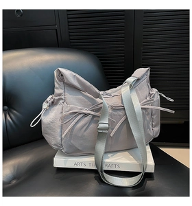 Détail du sac hobo en nylon gris clair avec nœuds de serrage latéraux sur cuir