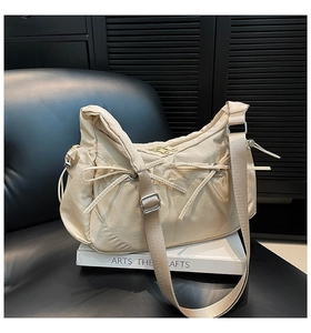Détail du sac demi-lune en nylon beige avec nœuds et bandoulière réglable pratique