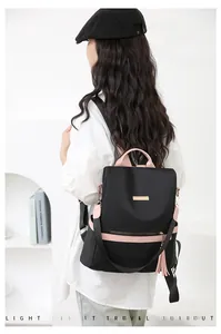 Detailed view of women's black nylon backpack with pink straps and multi-pocket design