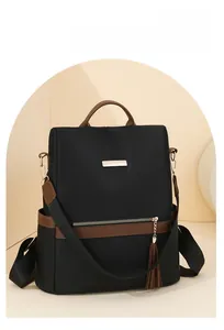 Detail of nylon backpack featuring brown leather trim and metal logo plate accents