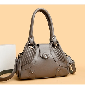 Close-up of textured khaki shoulder bag featuring pleated leather and metal twist lock