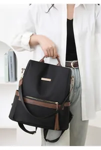 Detail of nylon backpack with brown leather handle and gold tassel zipper pull