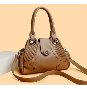 Detail view of caramel brown lychee leather handbag with vintage rivets and metal lock